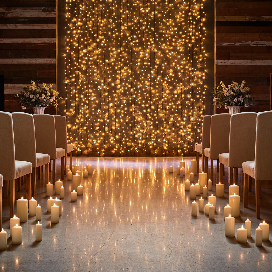 Warm white backdrop lights in a wedding ceremony featuring LED candles