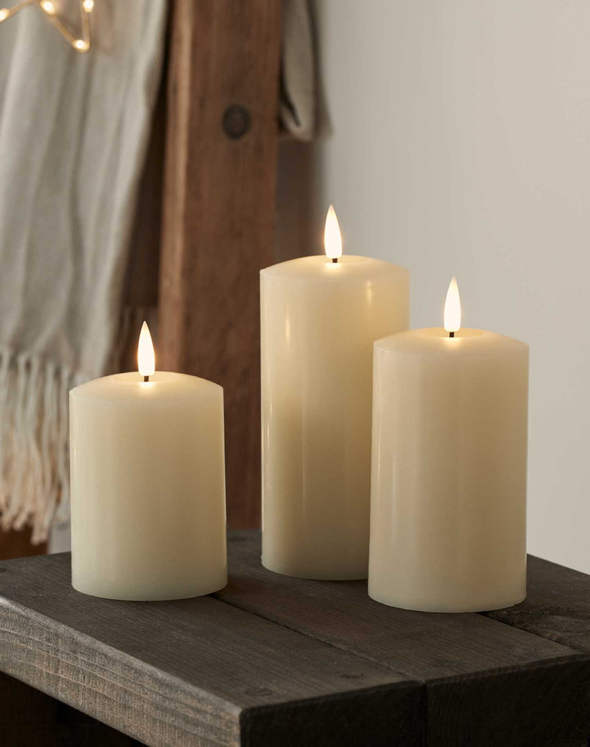 Trio of TruGlow® pillar candles styled on an indoor dining table