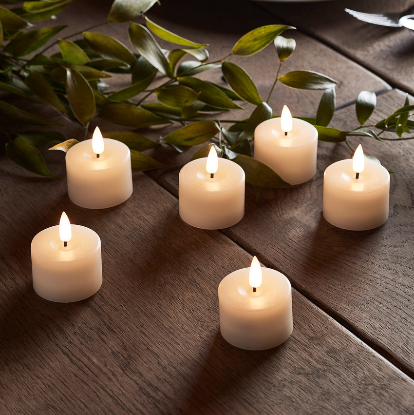 Set of four LED votive candles styled indoors on books