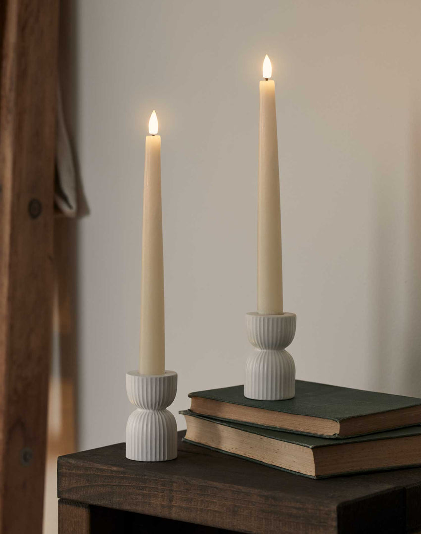 Set of four LED taper candles in holders in an indoor setting