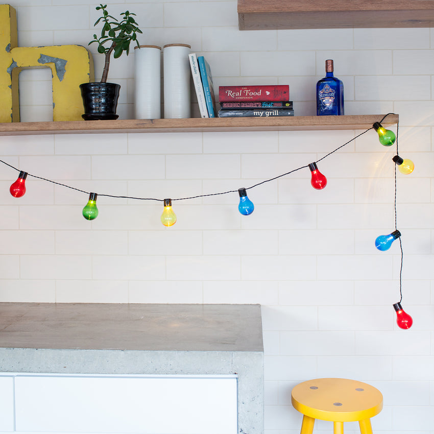 Multi coloured essential connect festoon lighting draped from a kitchen shelf