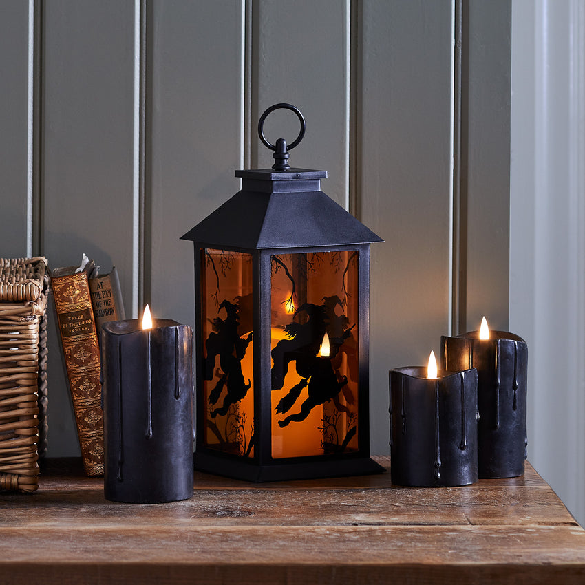 Trio of black dripping wax halloween pillar candles with a halloween lantern