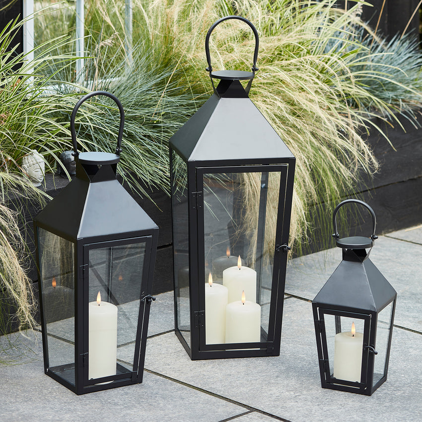 Trio of black metal lanterns with LED candles outdoors