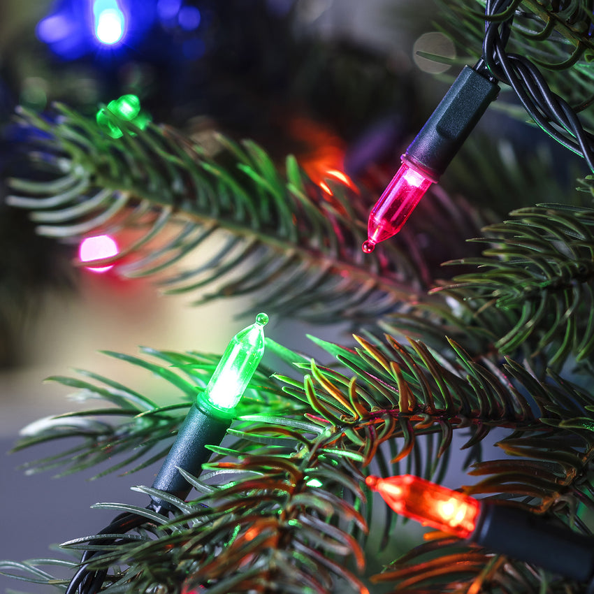 Zoom in of multi-coloured Christmas tree lights displayed on a Christmas tree