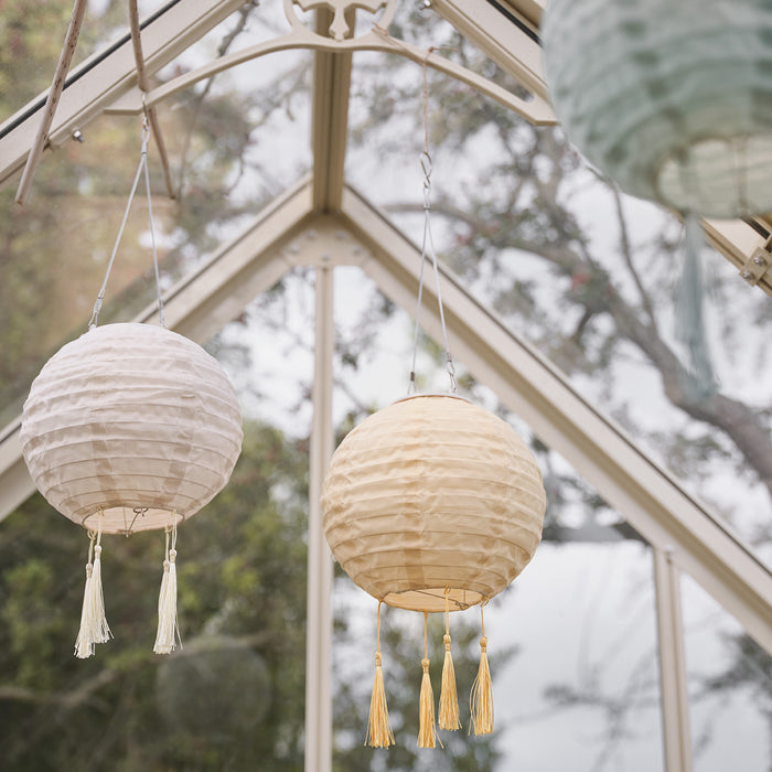 3 pastel lanterns hanging from a greenhouse roof