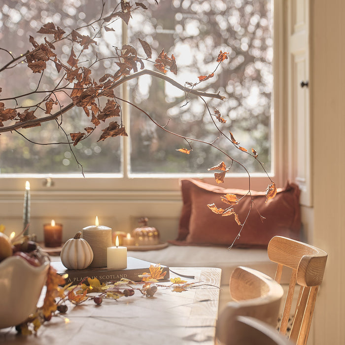 Autumn dining room window seat and table with foliage and LED candles