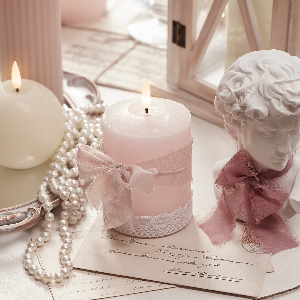 Pink LED candle with a pink ribbon rapped around it in a bow