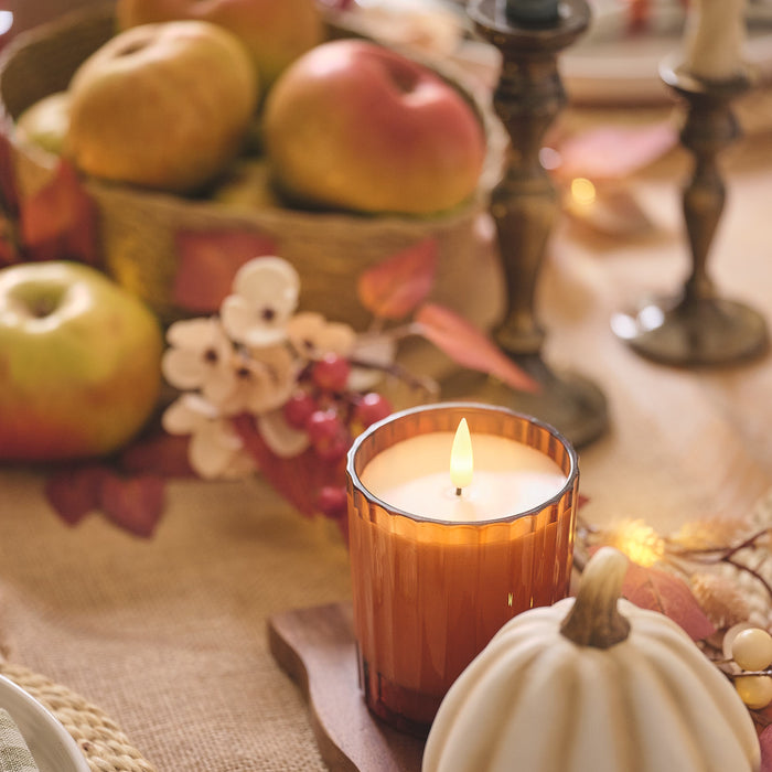 Burnt orange glass candle jar on an autumnal dining table