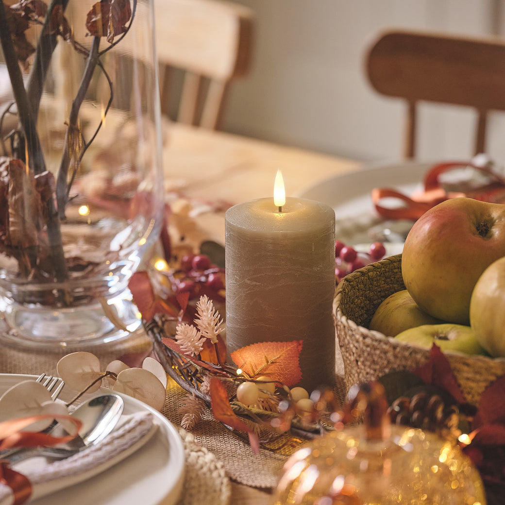 Distressed taupe pillar candle on an autumnal dining table