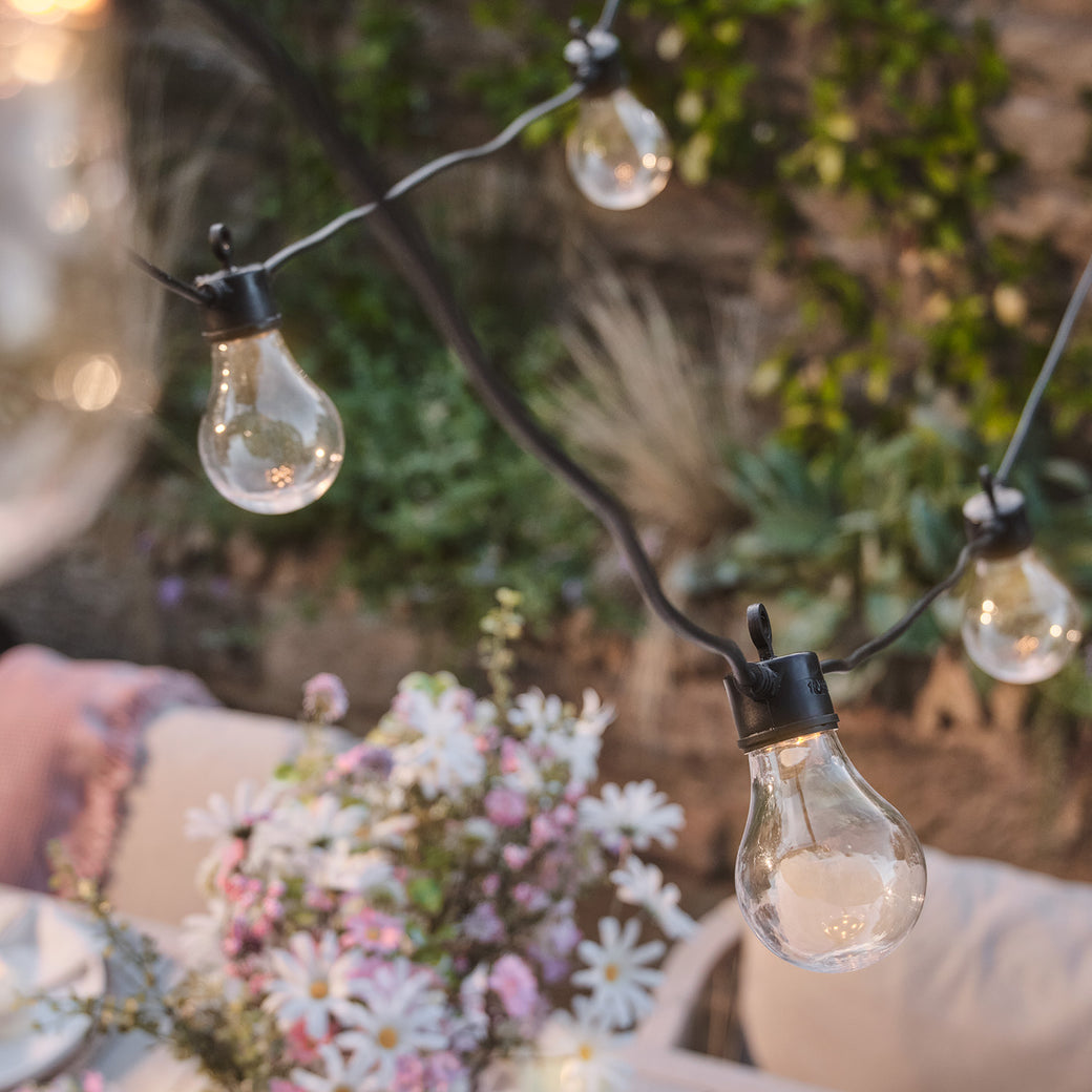 Warm white festoon lights hanging above a table outside