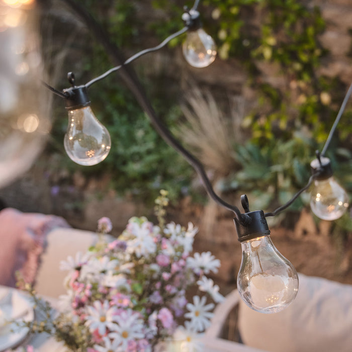Warm white festoon lights hanging above a table outside