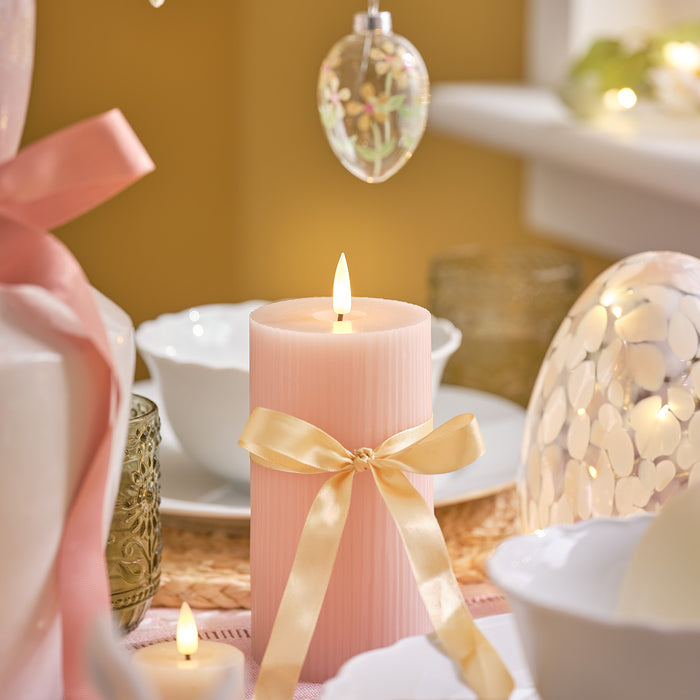 Pink LED candle with a yellow ribbon wrapped around it in a bow