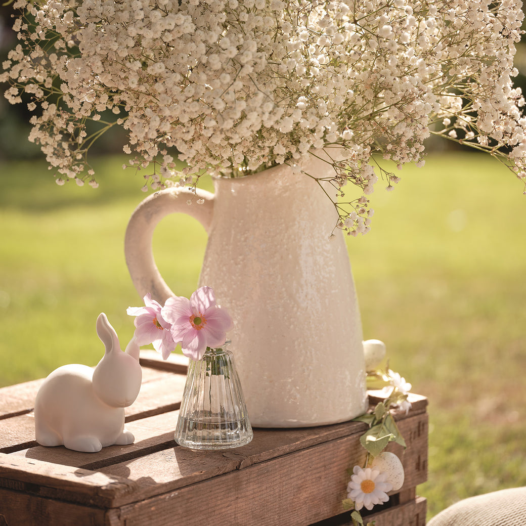 Vases of flowers on a wooden crate with ceramic bunny decoration