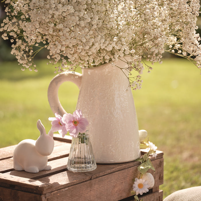 Vases of flowers on a wooden crate with ceramic bunny decoration