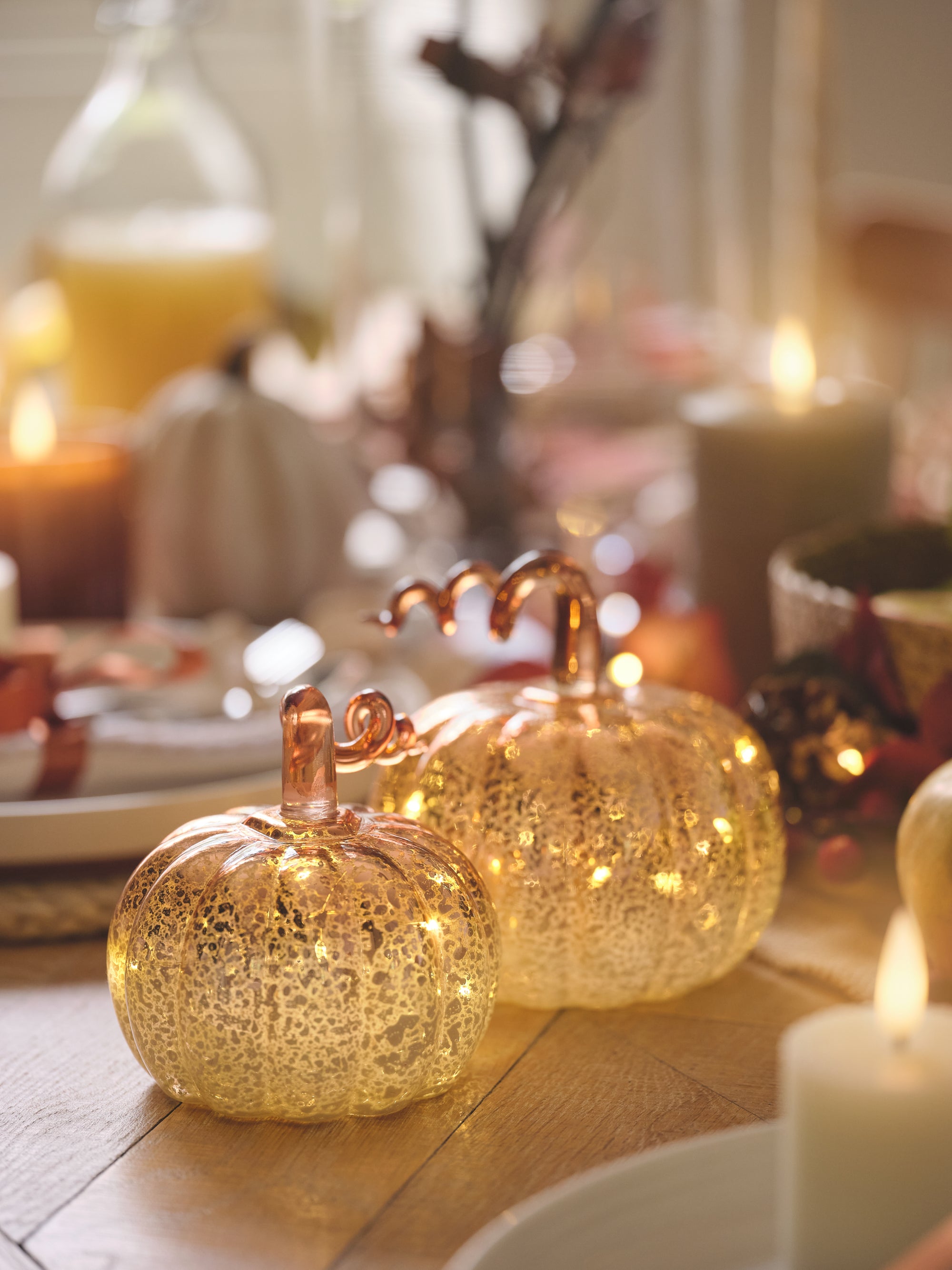 A pair of light up mercury glass pumpkins on a dining table