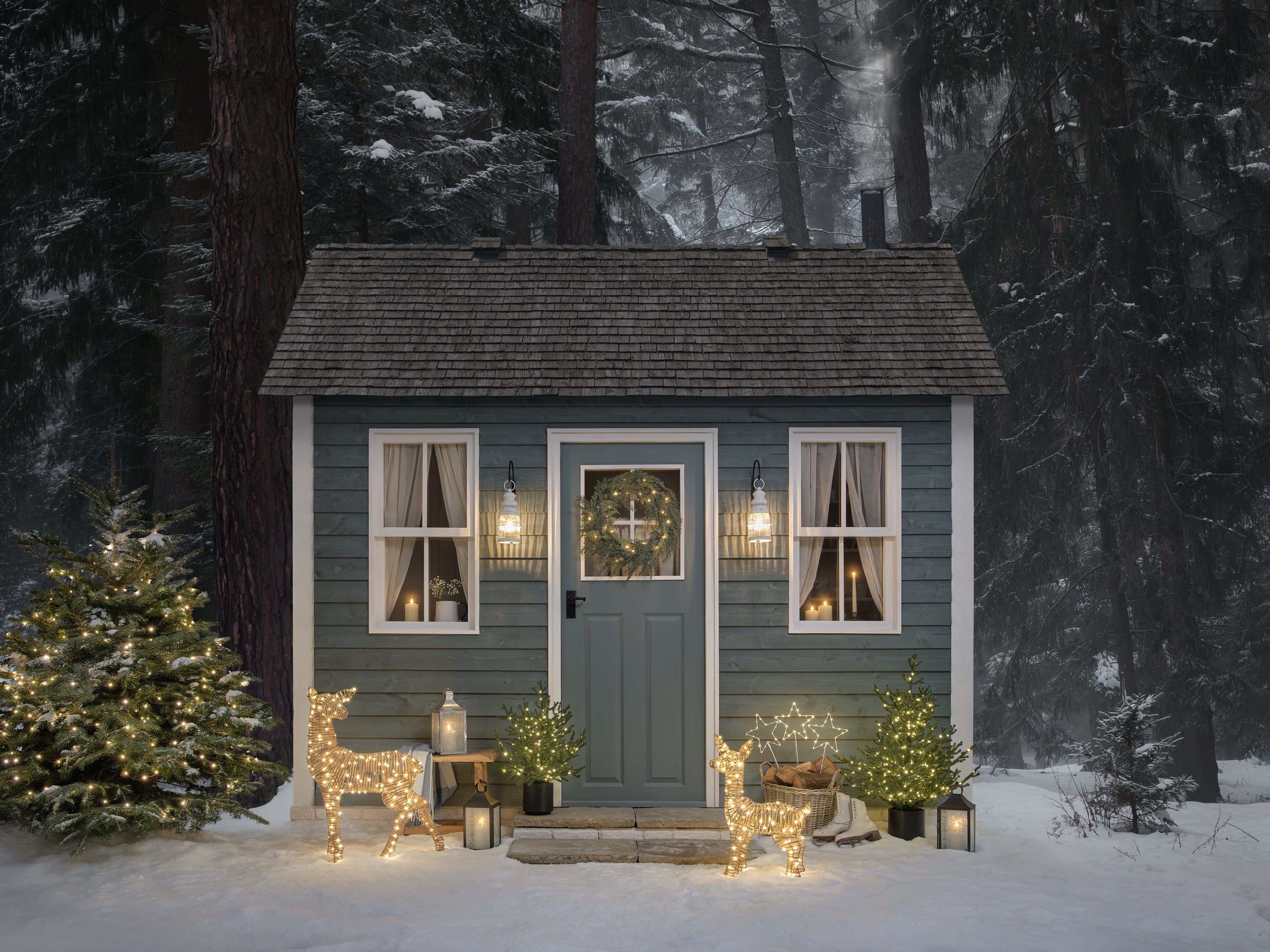 A front garden decorated for Christmas with light up reindeer, lanterns, and foliage