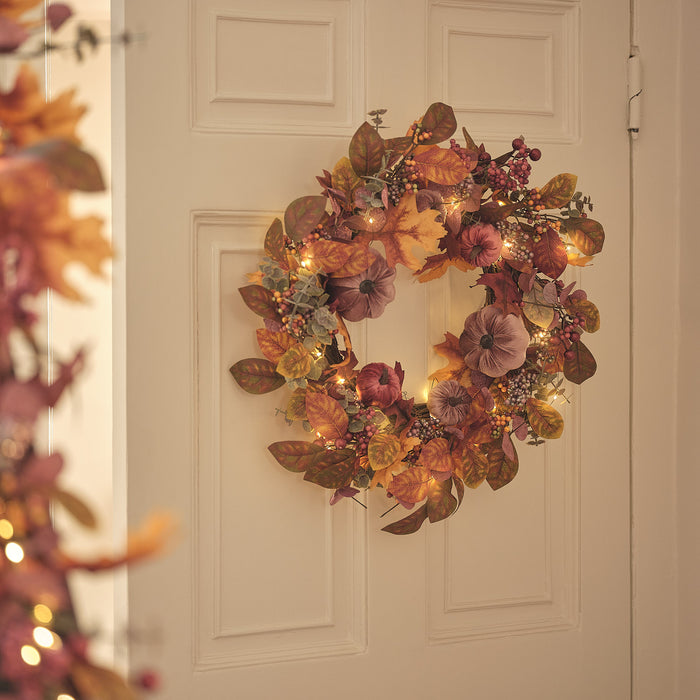 A velvet pumpkin wreath hanging on a door
