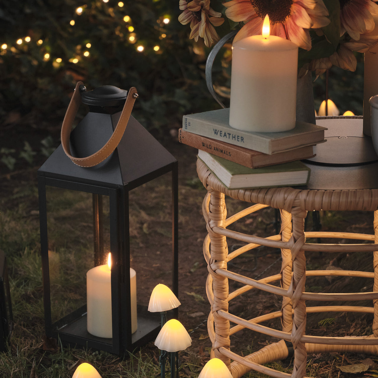 Large black lantern with a leather handle next to a wicker garden table