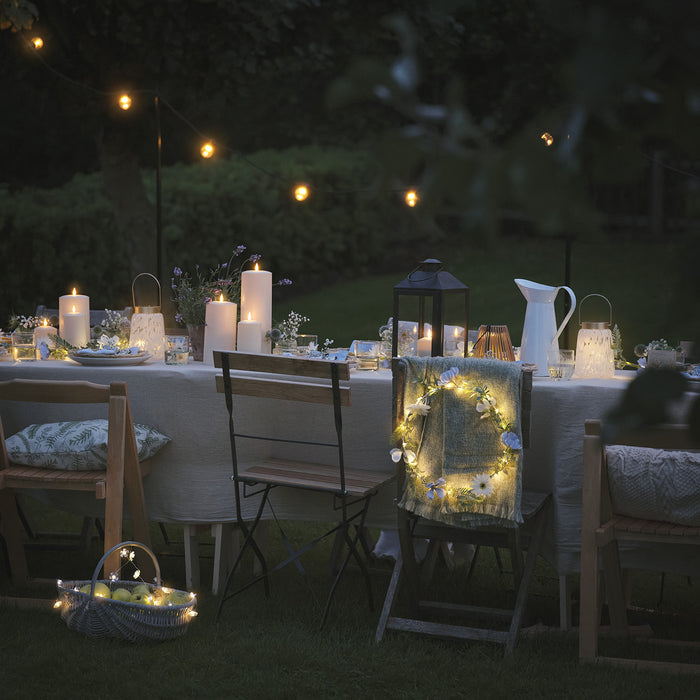 Outdoor dining table set with wreath, LED candles, and lanterns