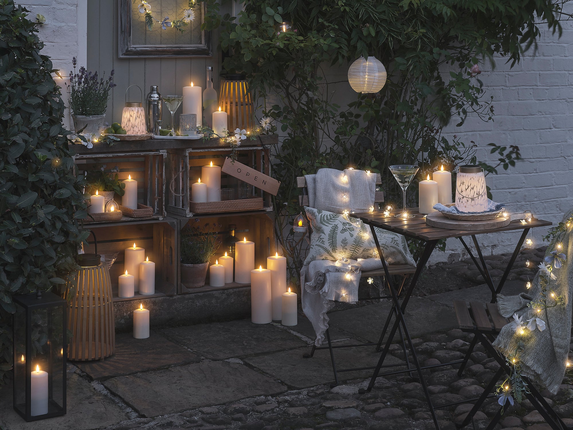 A patio with a table and chairs, as well as LED candles and lanterns