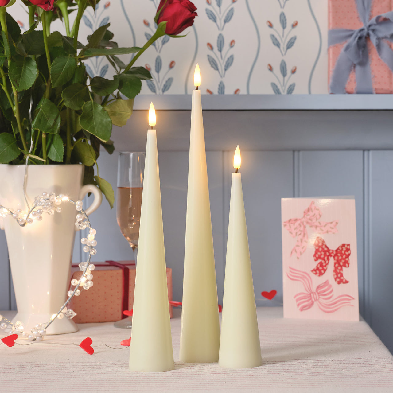 Three LED cone candles of different sizes on a table