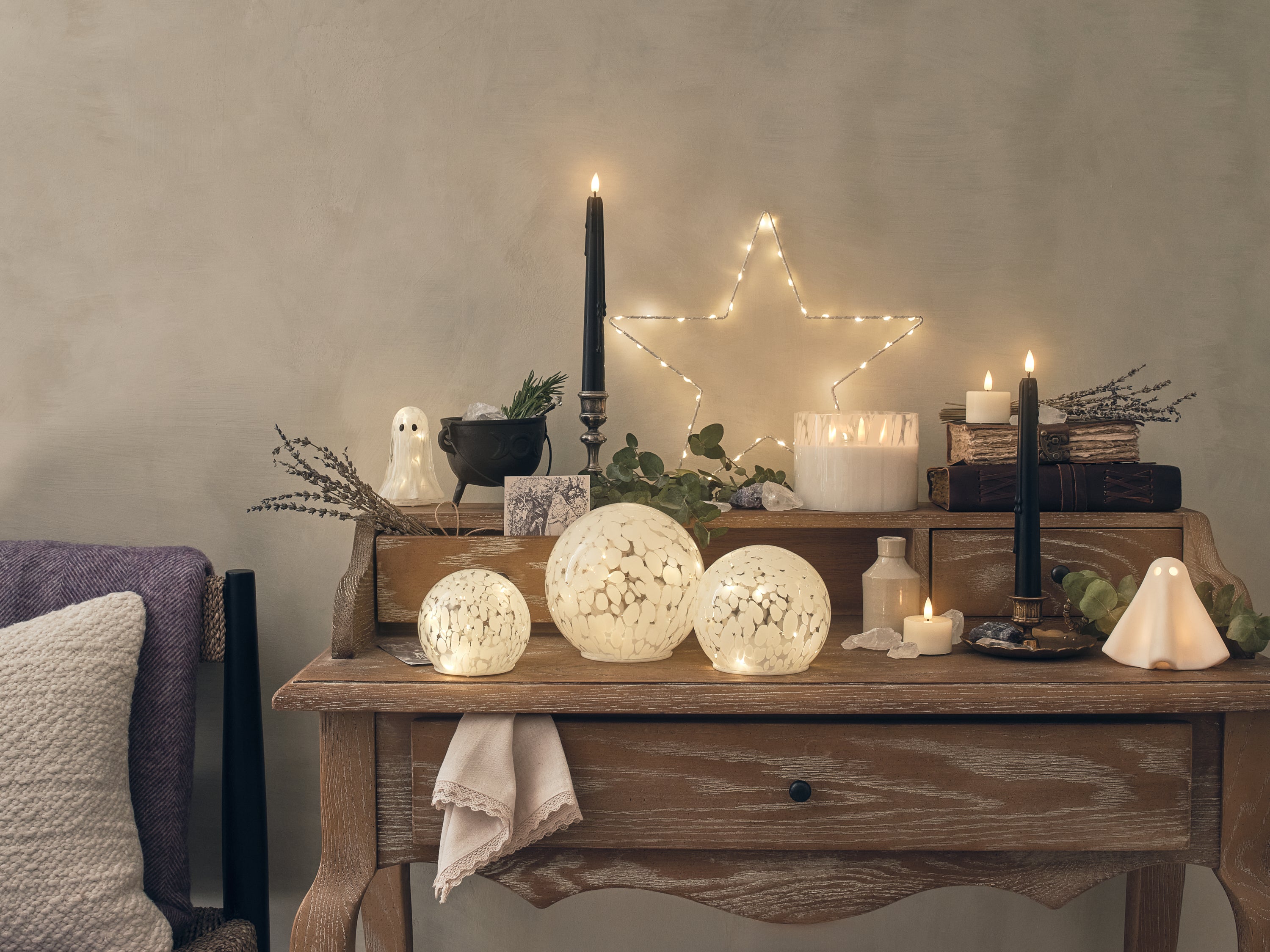 A dresser decorated with LED candles and ghost decorations