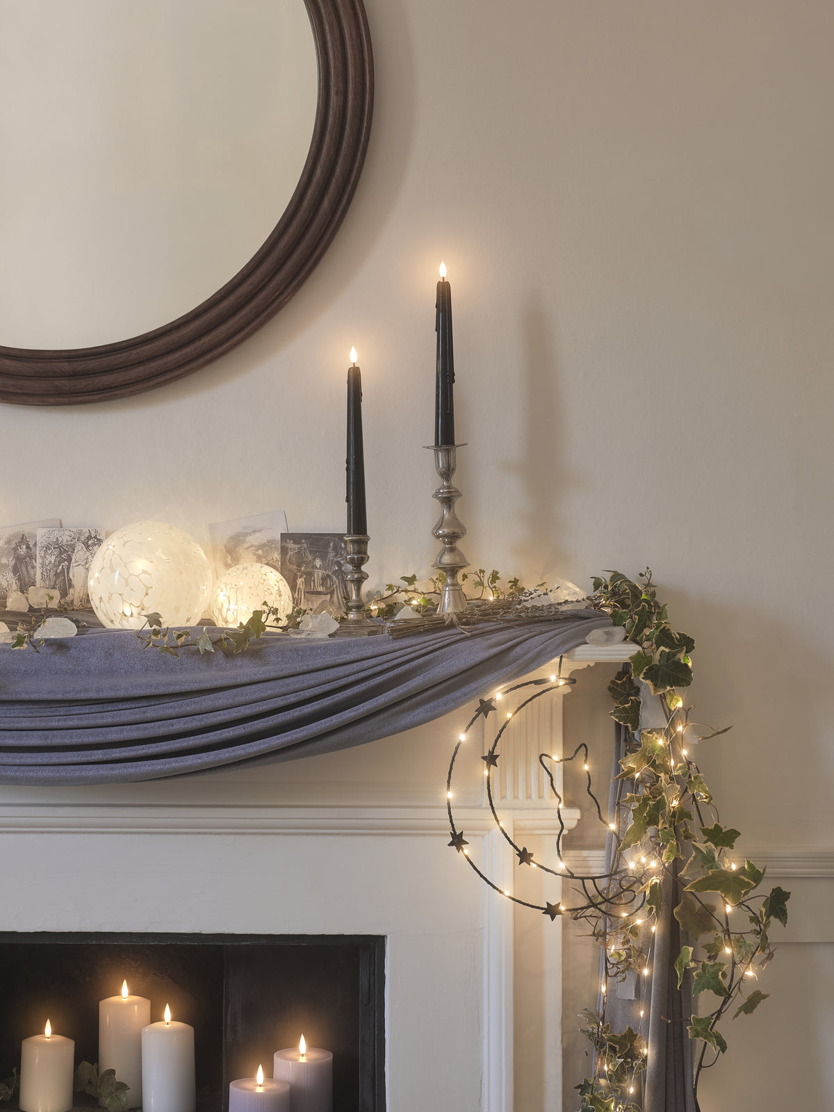 A fireplace mantel decorated with black LED candles and Halloween decorations