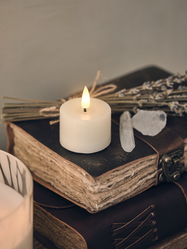 A mini votive candle on a spell book