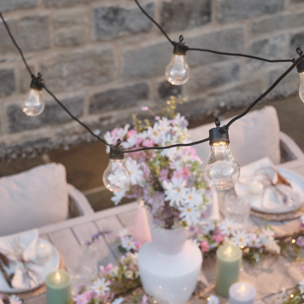 Festoon lights hanging above an outdoor dining table