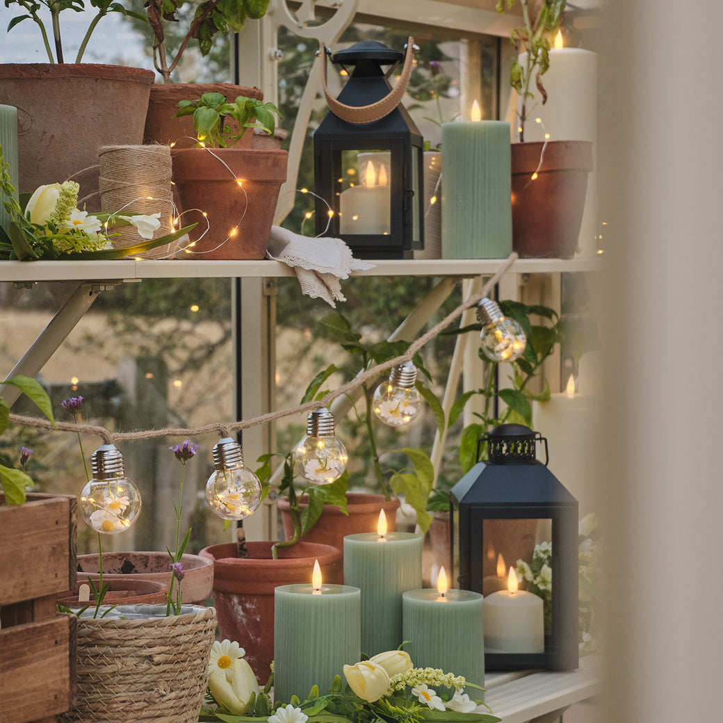 Greenhouse shelves lined with LED candles, micro lights, lanterns, and daisy festoon lights.
