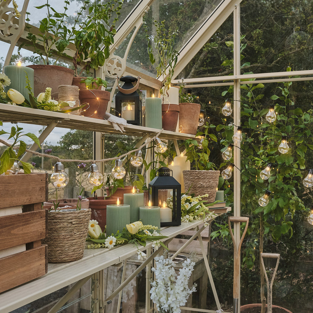 Inside a greenhouse with festoon lights, LED candles, and lanterns