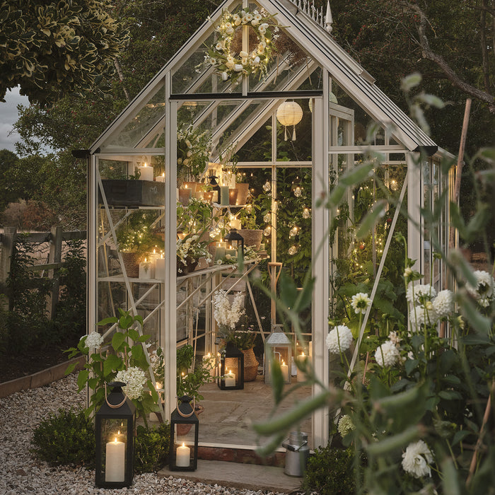 A greenhouse lit with LED candles, lanterns, and festoon lights