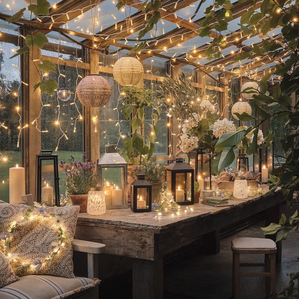 Scandi style greenhouse with fairy lights, lanterns, and LED candles