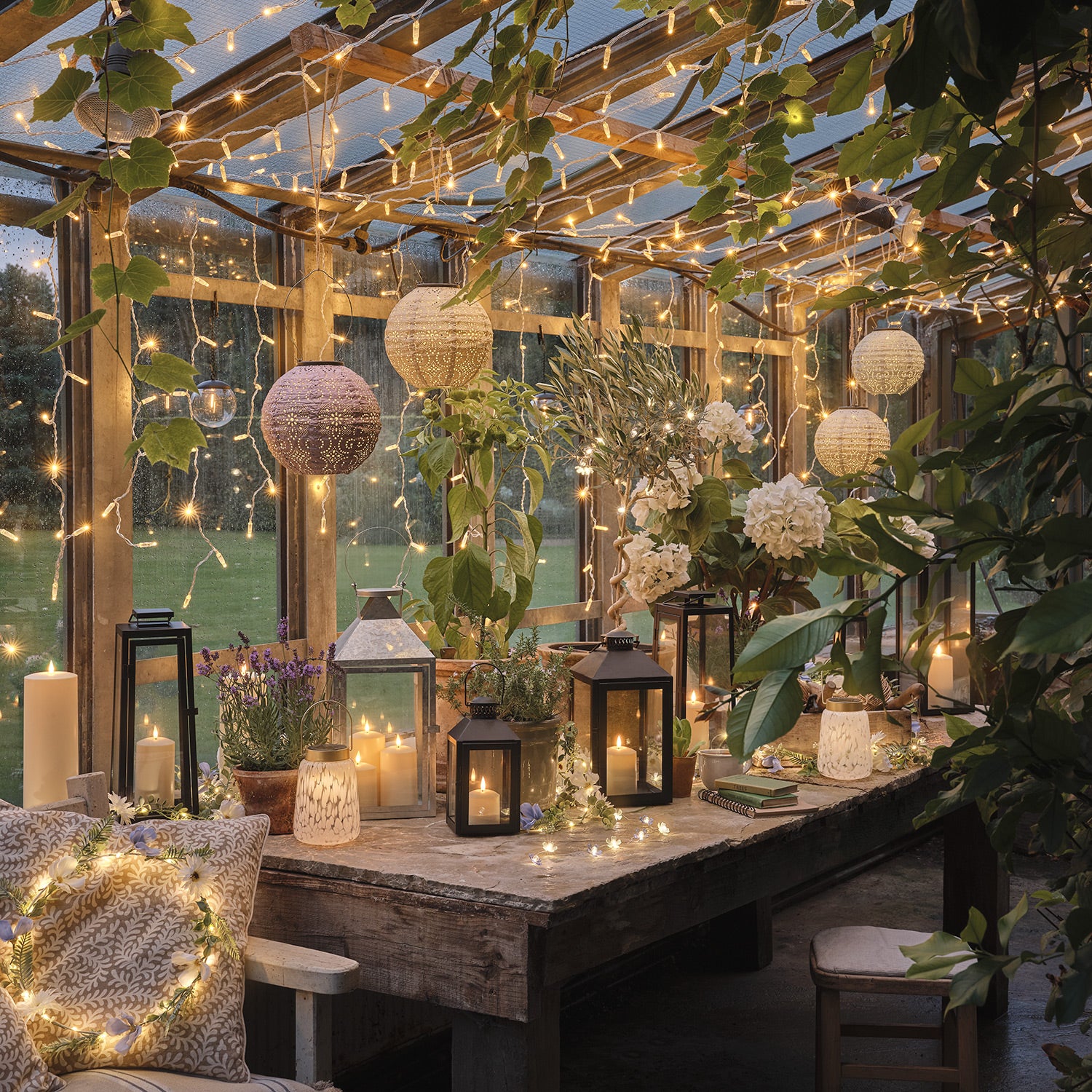 Summer greenhouse lit with fairy lights, LED candles, and lanterns