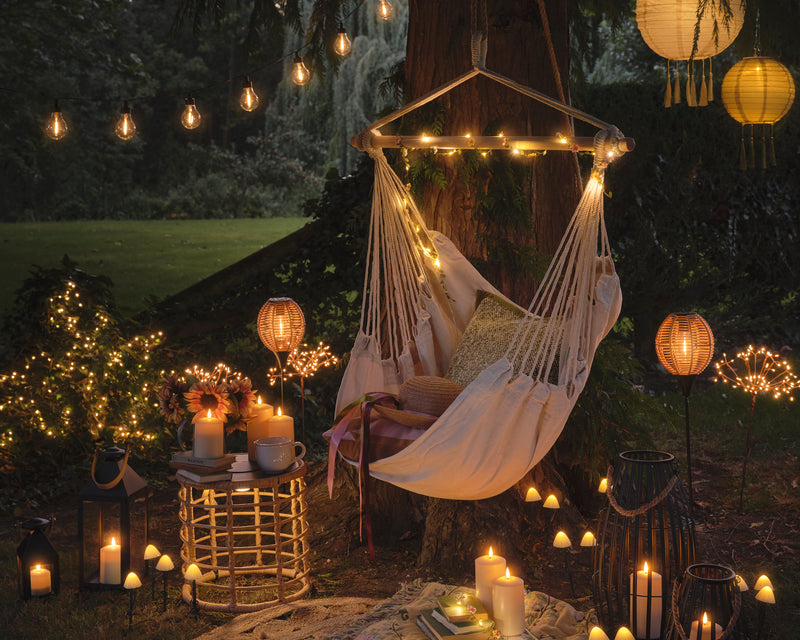 Hanging garden seat with fairy lights, festoons, LED candles, and stake lights.