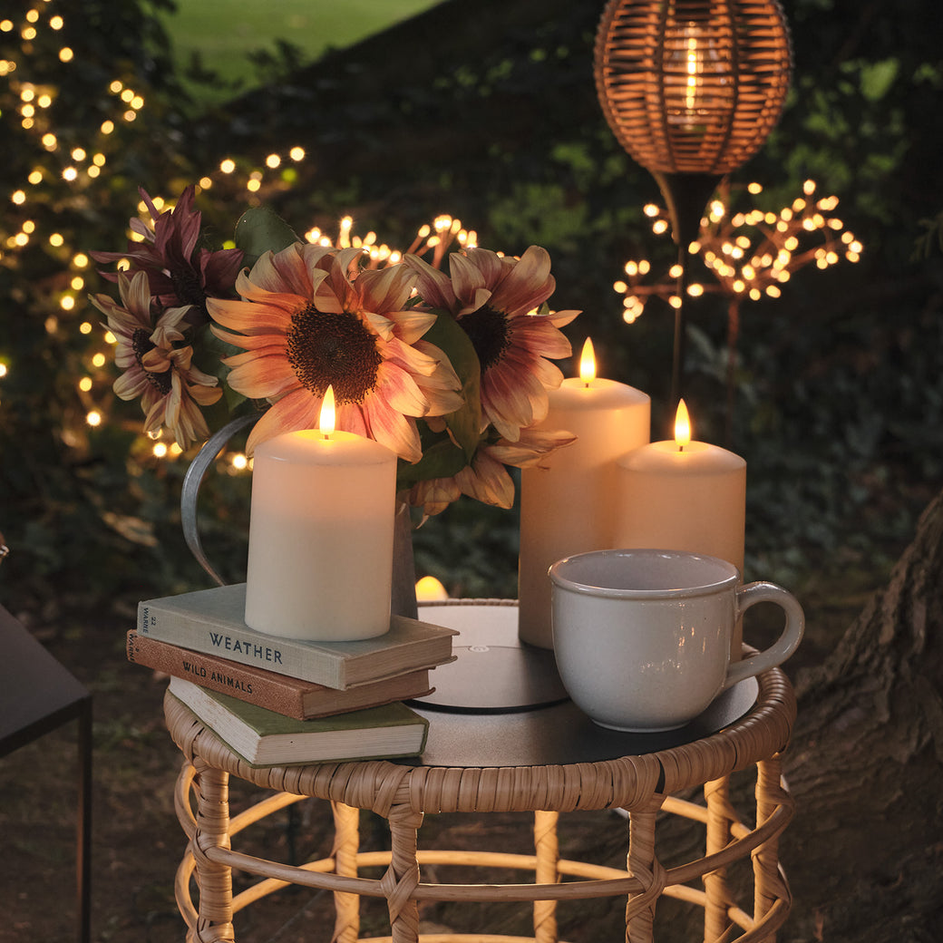 LED candles and flowers on an wicker garden table