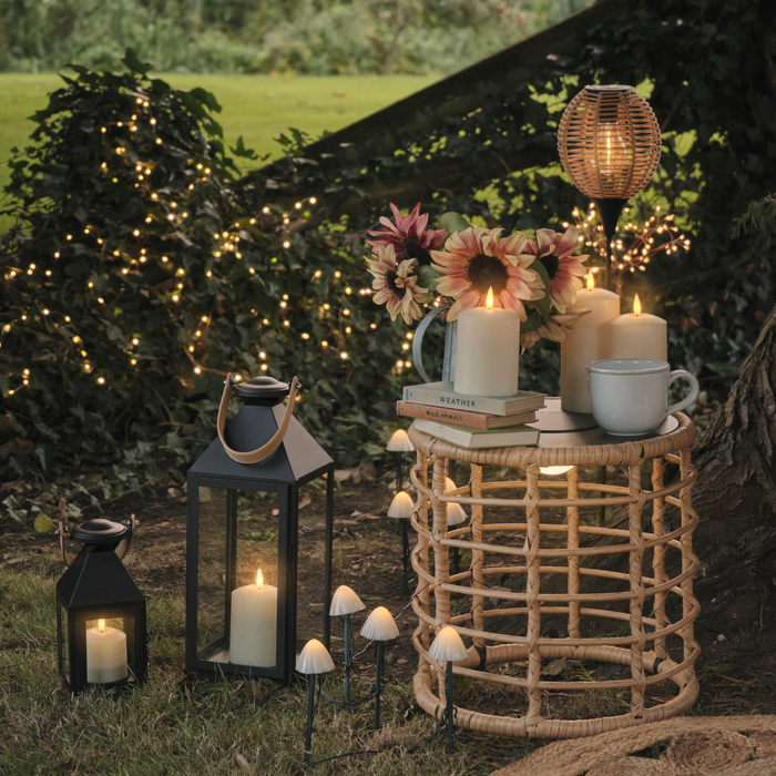 Wicker garden table with LED candles, stake lights, and lanterns