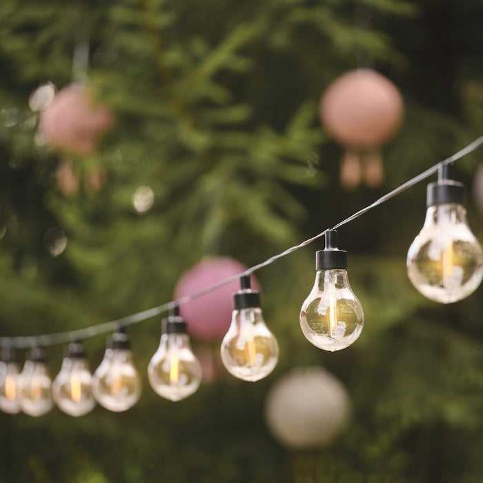 Warm white vintage solar festoon lights hang next to colourful lanterns