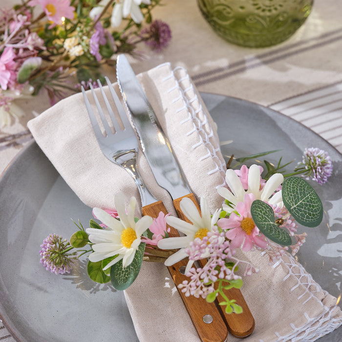 A small daisy wreath wrapped around a place setting on a dining table