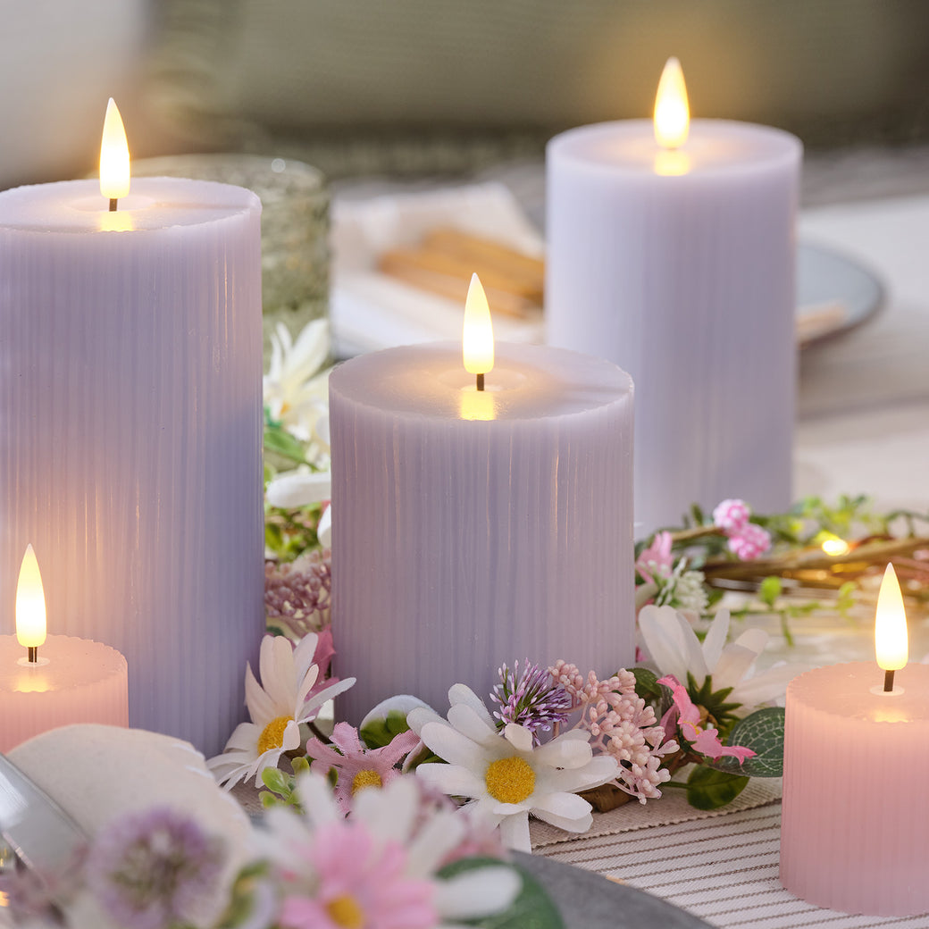 Pastel lilac and pink LED candles on a dining table with a floral candle holder